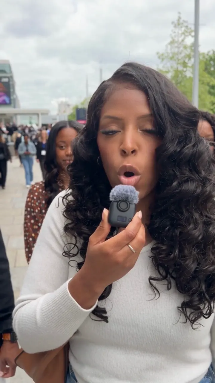 Ri Michelle holding a microphone interviewing women outside a busy conference venue
